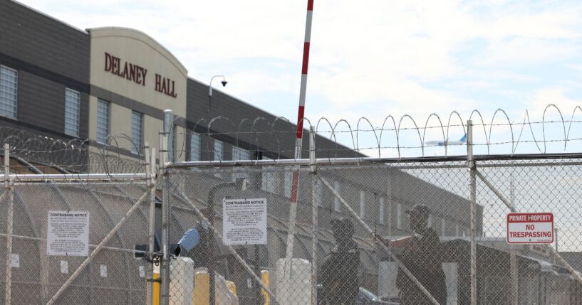 Immigration and Customs Enforcement agents stand guard behind the gate as protestors gather at Delaney Hall, which is being used as an Immigration and Customs Enforcement detention center in Newark, New Jersey, on May 26, 2026.