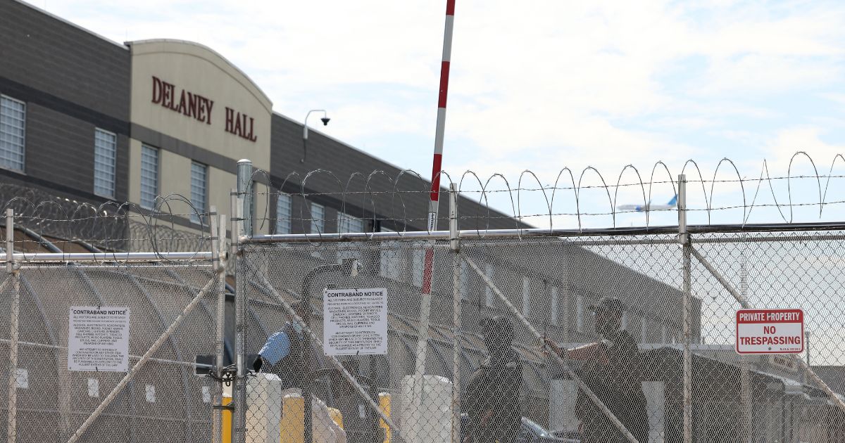 Immigration and Customs Enforcement agents stand guard behind the gate as protestors gather at Delaney Hall, which is being used as an Immigration and Customs Enforcement detention center in Newark, New Jersey, on May 26, 2026.