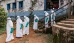 Health workers wearing protective equipment walk outside the General Referral Hospital during the Ebola outbreak response on May 21, 2026, in Mongbwalu, Democratic Republic of Congo.