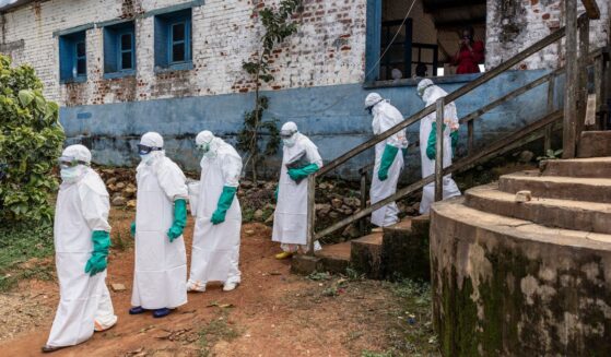 Health workers wearing protective equipment walk outside the General Referral Hospital during the Ebola outbreak response on May 21, 2026, in Mongbwalu, Democratic Republic of Congo.