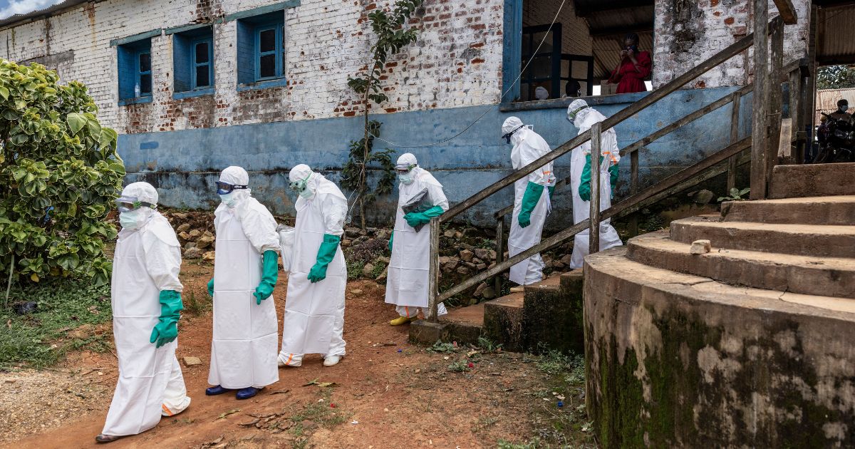 Health workers wearing protective equipment walk outside the General Referral Hospital during the Ebola outbreak response on May 21, 2026, in Mongbwalu, Democratic Republic of Congo.