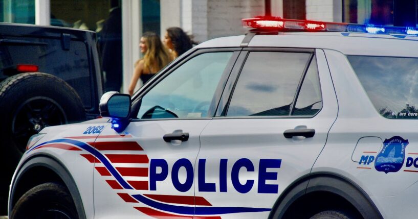 A Metropolitan Police cruiser responds to a call in historic Georgetown as two women walk by in the background, in Washington, D.C., on Aug. 16, 2024.