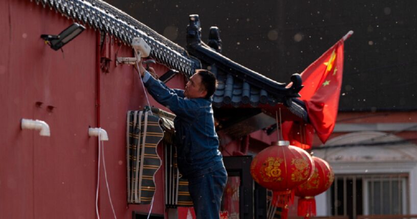 A man sets up a surveillance camera outside a restaurant with a Chinese national flag in Beijing on Friday as the capital city prepared for President Donald Trump's arrival.