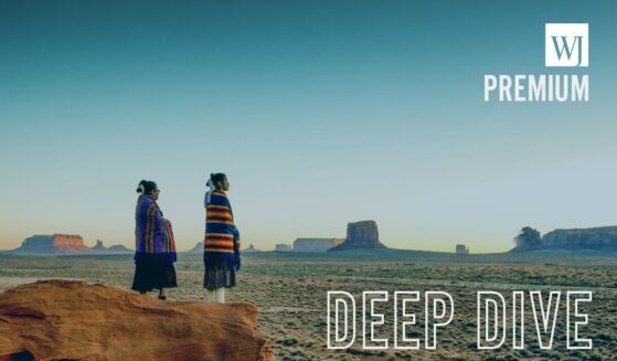 Navajo girls wrapped in handwoven traditional blankets enjoying a grand sunrise in Monument Valley.
