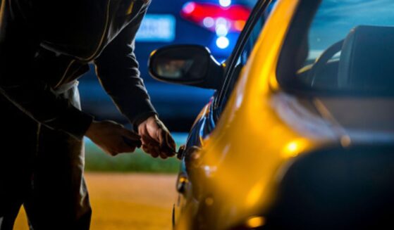 A man tries to pick a lock on a car.