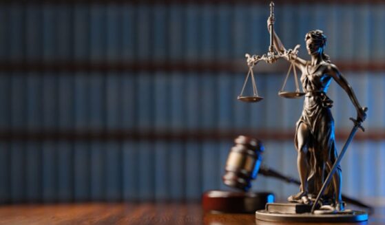 A statuette of Lady Liberty stands beside a gavel and a wooden block.