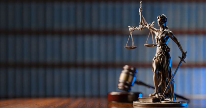 A statuette of Lady Liberty stands beside a gavel and a wooden block.