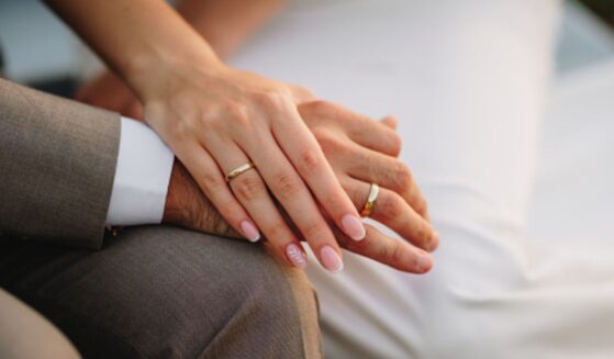 A groom and a bride hold hands.