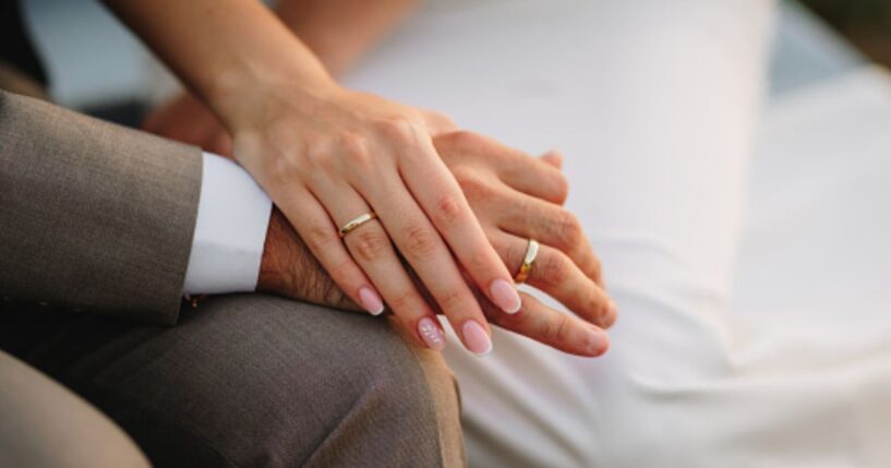A groom and a bride hold hands.