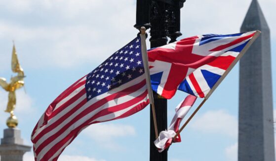 The United States flag and United Kingdom flag wave together on a light pole.