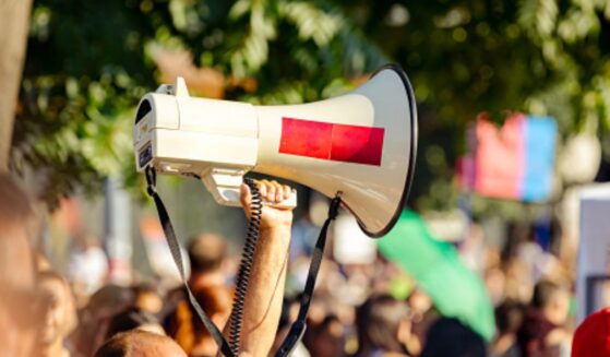 A protestor raises a megaphone amongst a crowd.