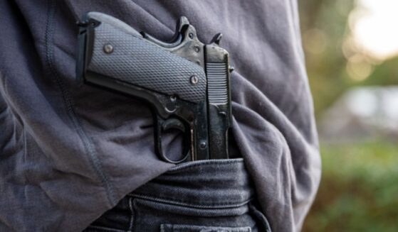 Man carries gun in his pants as he walks in a field.