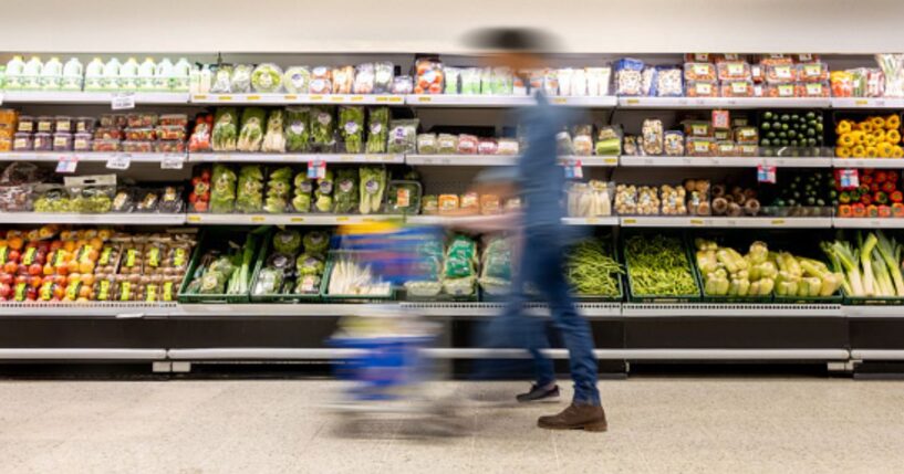 A man walks through a grocery store aisle.