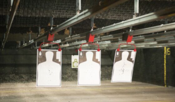 Indoor gun range targets hang from a bar on the ceiling.