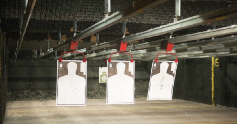Indoor gun range targets hang from a bar on the ceiling.