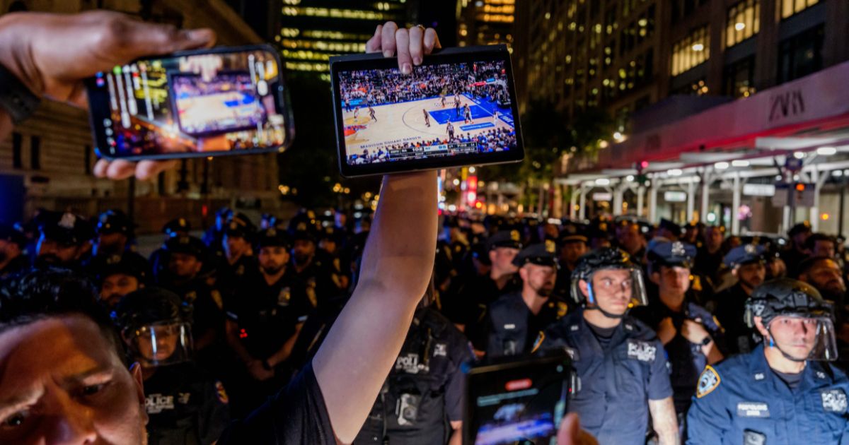 A Knicks fan holds up a screen of the NBA finals game between New York City and San Antonio at a watch party in Bryant Park for Game 3 of the Finals in New York City on June 8, 2026.