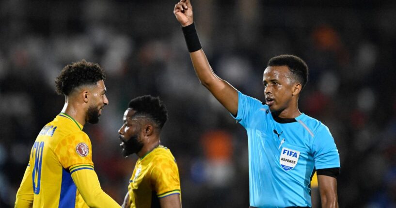 Somali FIFA referee Omar Abdulkadir Artan holds up a card during the Africa Cup of Nations Group F football match between Gabon and Ivory Coast in Marrakech on Dec. 31, 2025.