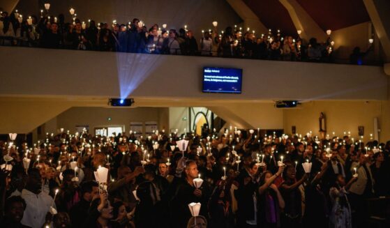 Christians hold candles during worship in a church in Lyon, France, on April 4, 2026.
