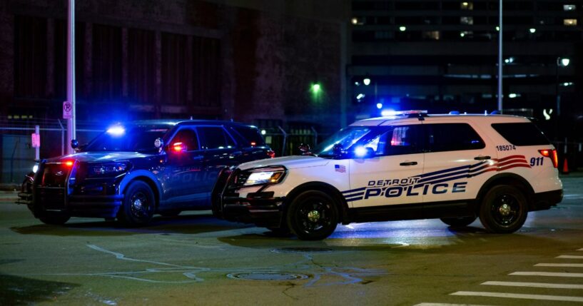 Two Detroit police vehicles flash their lights in the street on Dec. 20, 2020.