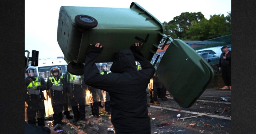 A man throws a garbage bin Tuesday as protesters confront riot police near the location where Henry Nowak died in Southampton, England.
