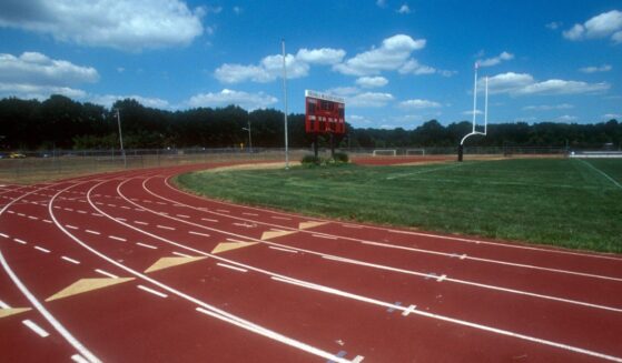 A high school running track and field with a goal post.