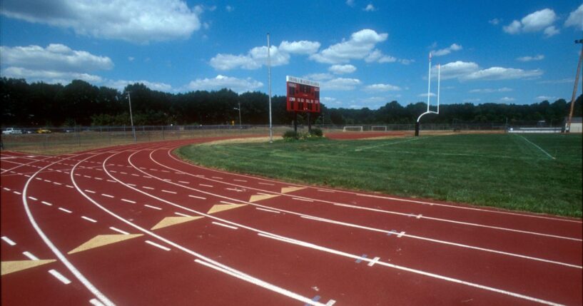A high school running track and field with a goal post.
