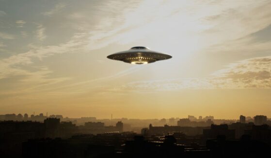A strange flying machine in the shape of a saucer, silently hovering in the air. It emits a bright light and seems to scan the surrounding space with a beam.