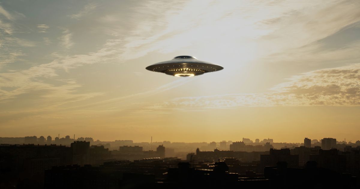 A strange flying machine in the shape of a saucer, silently hovering in the air. It emits a bright light and seems to scan the surrounding space with a beam.