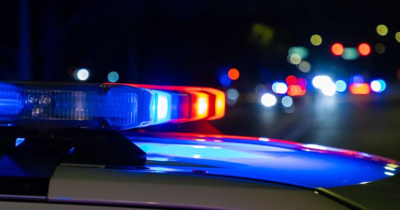 A crime scene in a city at night with blue and red police lights.
