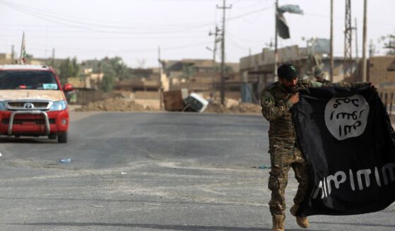 An Iraqi member of the Hashed al-Shaabi (Popular Mobilisation units) carries an upside-down Islamic State group flag in the city of al-Qaim, in Iraq's western Anbar province near the Syrian border, as they fight against remnant pockets of Islamic State group jihadists on Nov. 3, 2017.
