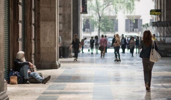 A homeless man sit in the street watching people passing by in Milan, Italy, on May 7, 2015.