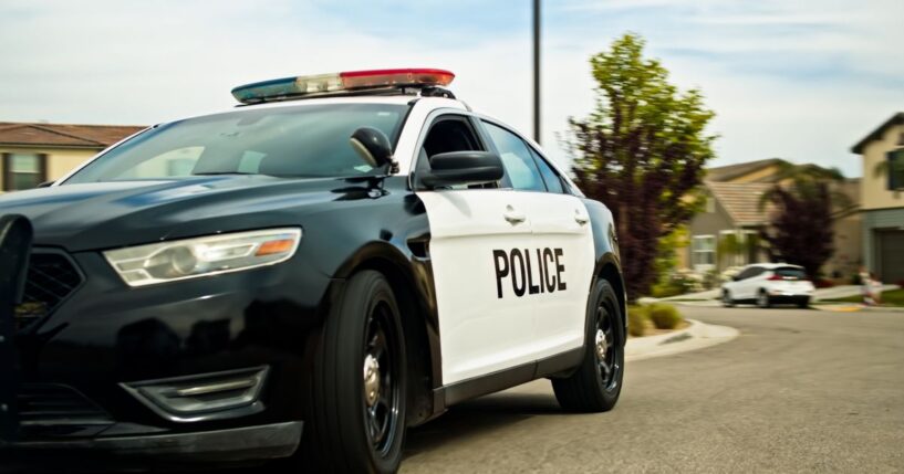 A locked off shot of a police car in a California suburb on a mostly clear day in spring.