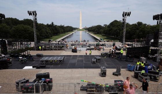 With the Washington Monument and the Reflecting Pool of the National Mall in the background, workers construct a stage for part of the upcoming Ultimate Fighting Championship Freedom 250 event in Washington.