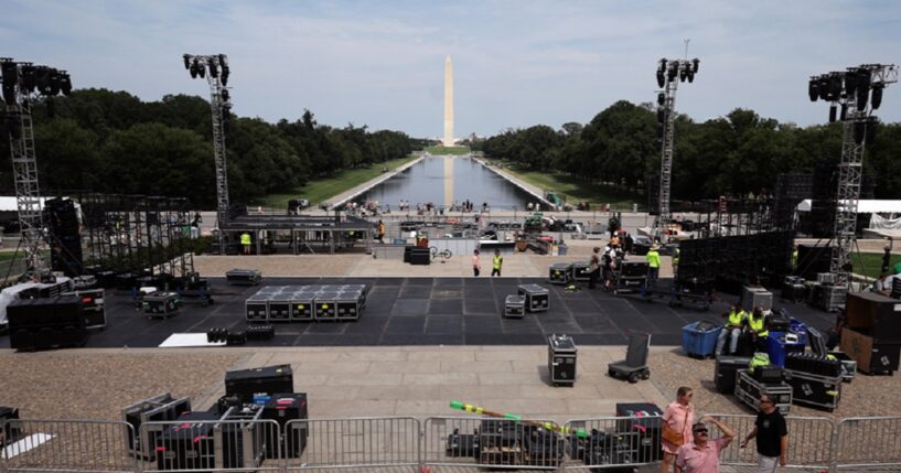 With the Washington Monument and the Reflecting Pool of the National Mall in the background, workers construct a stage for part of the upcoming Ultimate Fighting Championship Freedom 250 event in Washington.