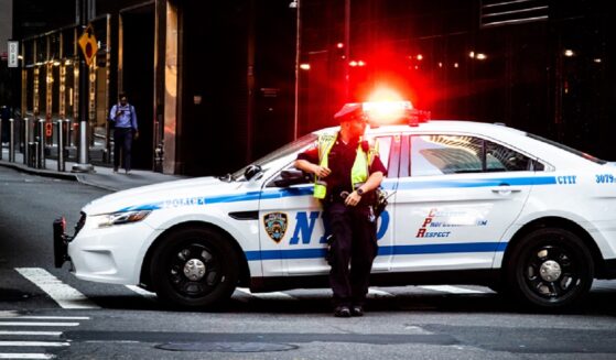 A New York City police officer is pictured in a May 2019 file photo with his patrol vehicle's lights flashing.