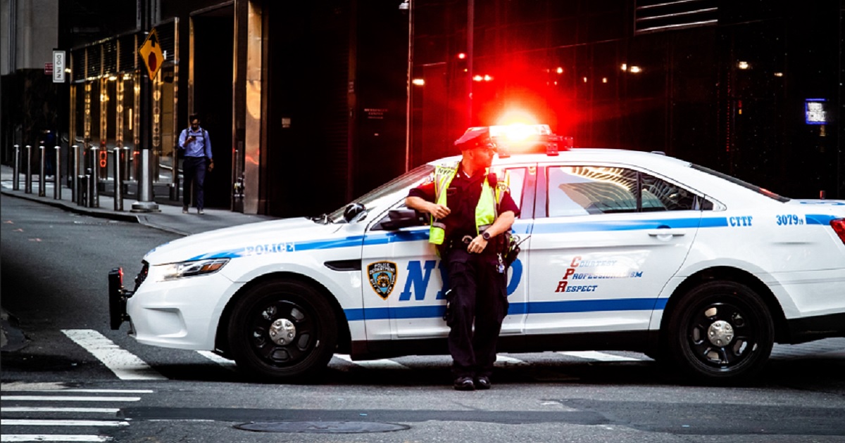 A New York City police officer is pictured in a May 2019 file photo with his patrol vehicle's lights flashing.