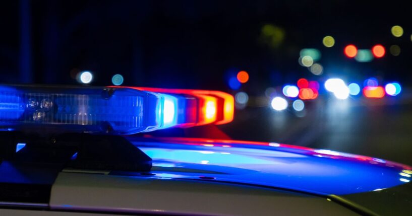A crime scene in a city at night with blue and red police lights.
