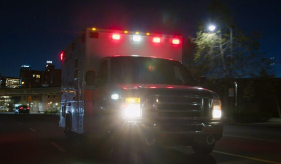 An ambulance driving through a downtown district at night.