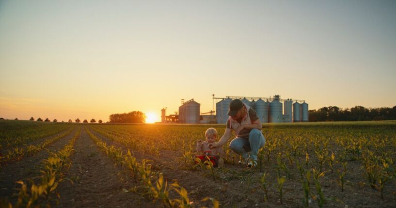A mother and toddler son playing with a toy tractor.