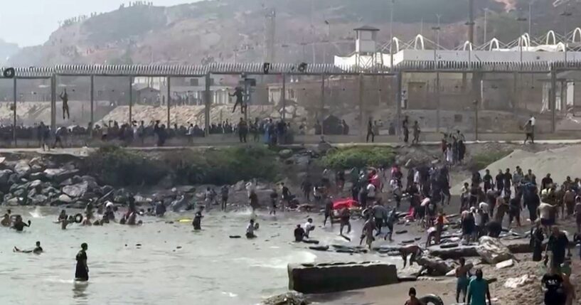 This video frame grab obtained from an AFP video shows migrants reaching the shore of Spanish north African exclave of Ceuta, after swimming around the border fence between Morocco and Spain, in Ceuta on July 30, 2026.