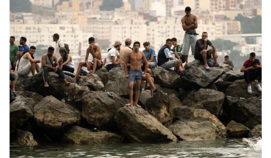 Migrants sit on rocks Friday after swimming through the waters close to the border with Morocco to enter Spain's north Africa's Ceuta enclave. Tens of thousands of migrants crossed overnight from Morocco into Ceuta, a territory with a population of about 80,000, a police source said.