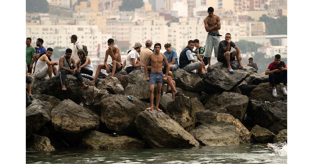 Migrants sit on rocks Friday after swimming through the waters close to the border with Morocco to enter Spain's north Africa's Ceuta enclave. Tens of thousands of migrants crossed overnight from Morocco into Ceuta, a territory with a population of about 80,000, a police source said.
