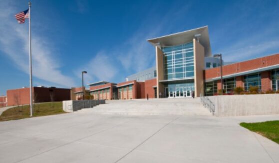 An American school building stands as an American flag waves in the wind.