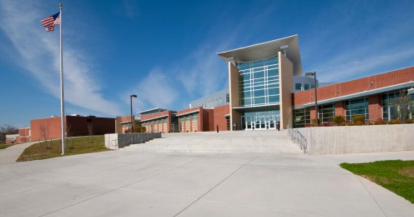 An American school building stands as an American flag waves in the wind.