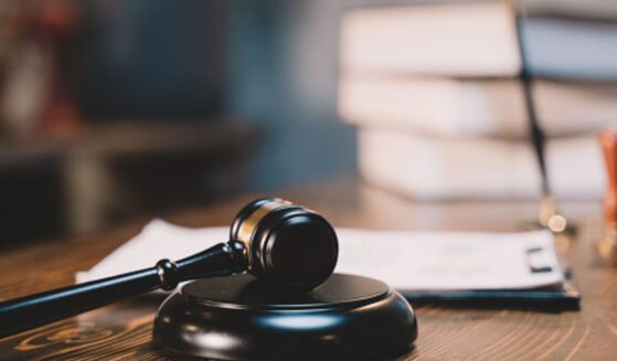 A black wooden gavel sits on a black wooden block in a bright room.