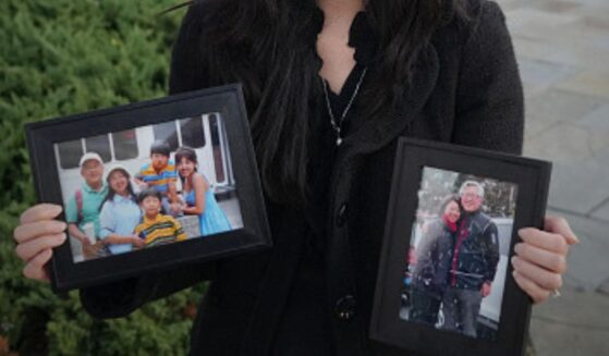 Grace Jin Drexel stands with photos of her father, Ezra Jin, on October 30, 2025 in Washington, D.C. during an interview.