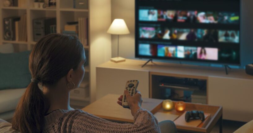 A young woman turns on the television in her living room.