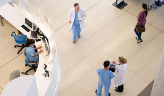 Hospital staff walk around in a hospital foyer.