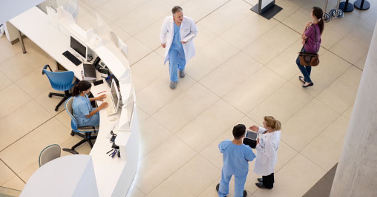 Hospital staff walk around in a hospital foyer.