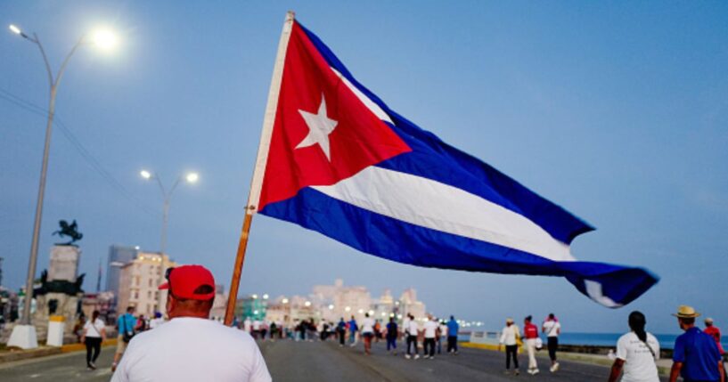 A man walks with a Cuban flag alongside the Havana waterfront on May 1, 2026.
